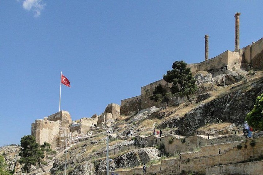 A historical site with ruins, a flag, and a clear sky. 2