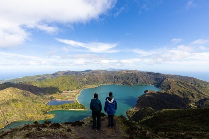 Two people standing on a hill overlooking a lake surrounded by hills. 5