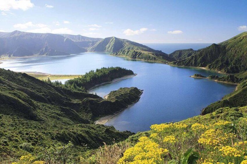 A lake surrounded by green hills and yellow flowers. 4