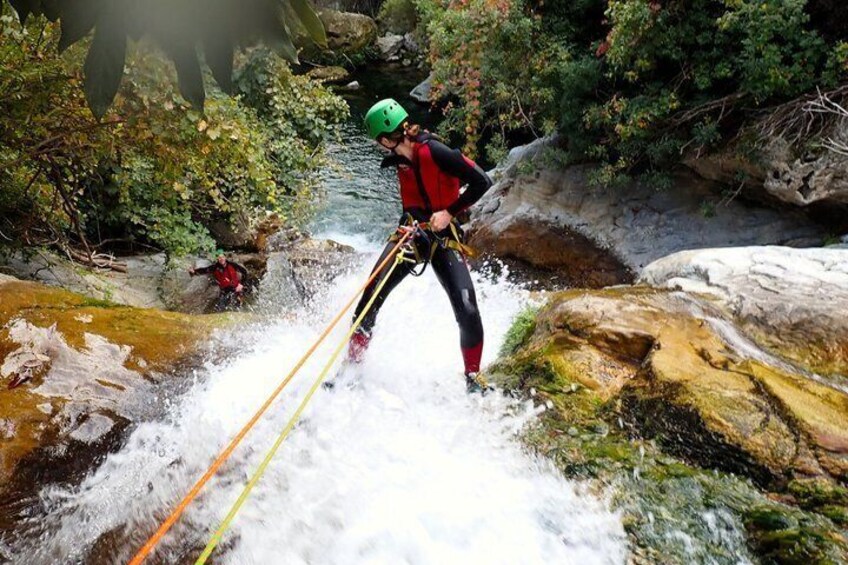 A person rappelling down a rocky waterfall. 1
