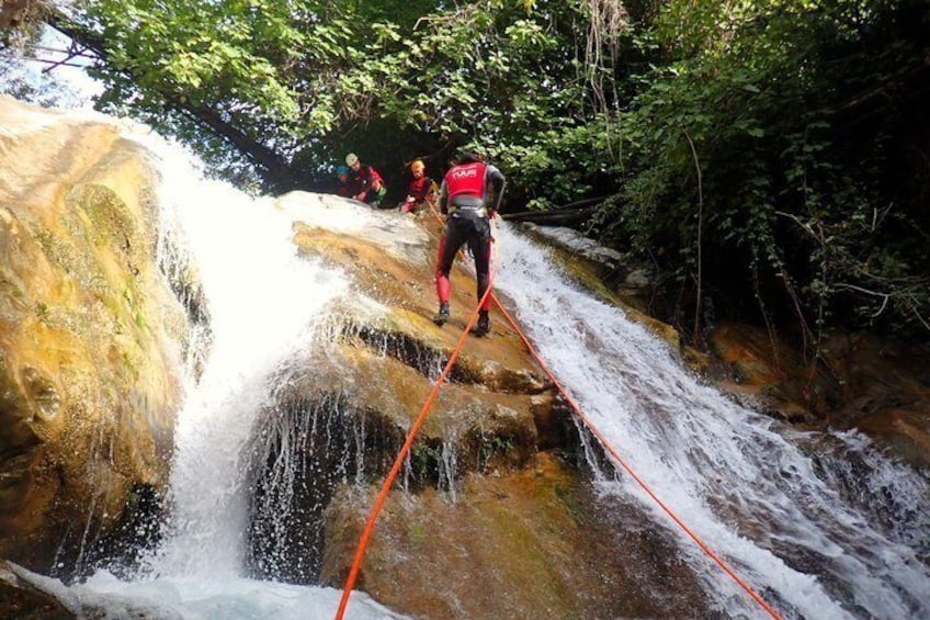 A person rappelling down a waterfall with a rope. 4
