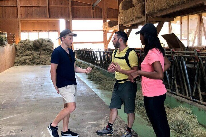 A barn interior with hay bales, feeding troughs, and a concrete floor. 3