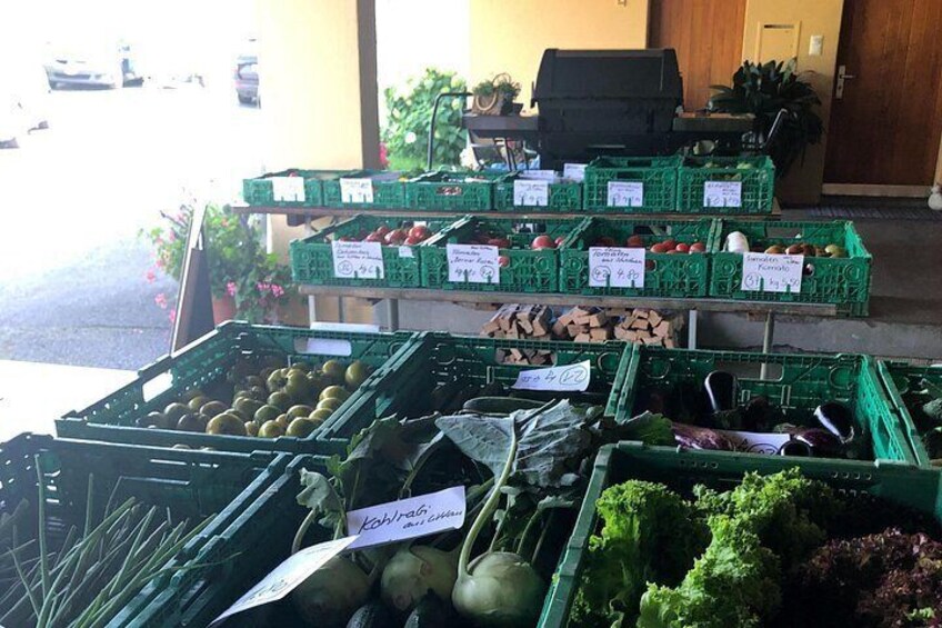 A produce stand with various fruits and vegetables in green crates, some labeled with handwritten notes. 4