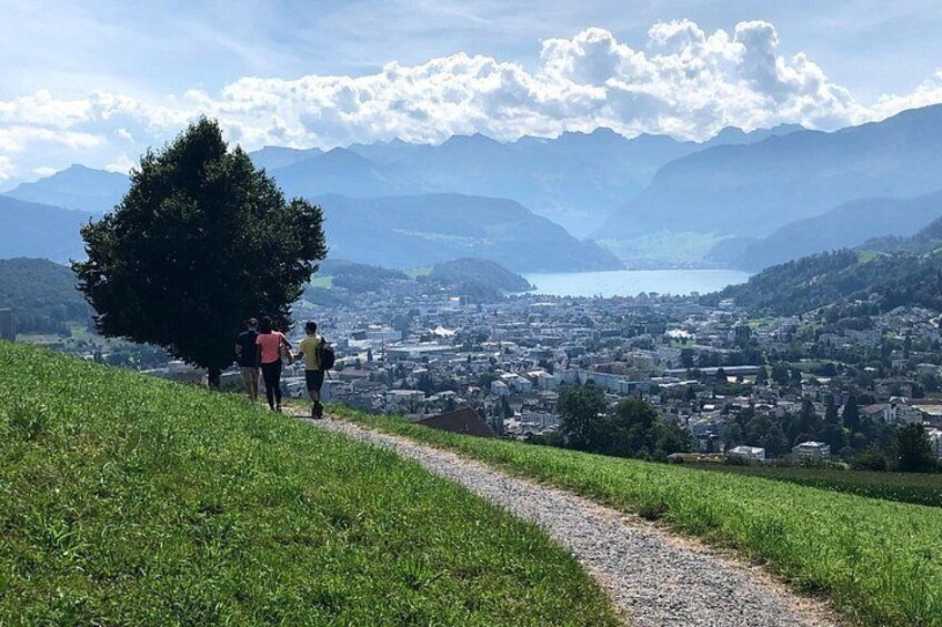 A hiking trail with a view of a town and mountains in the background. 1