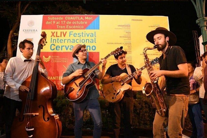 A group of musicians performing on stage at an outdoor event. 3
