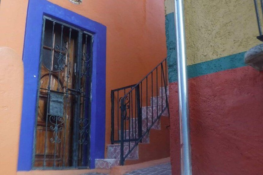 A building with a blue door, a metal gate, and a staircase. 4