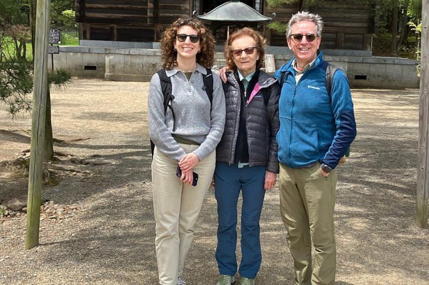 Three people standing in a park with a wooden structure in the background. 3