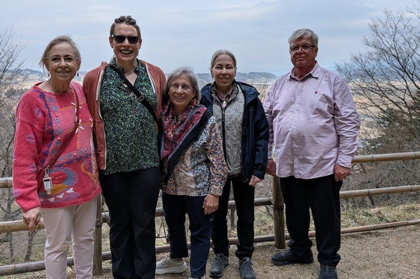 A group of people standing on a wooden fence with a dry, hilly landscape in the background. 5