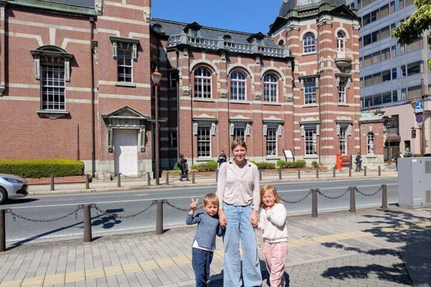 A historic building with red brick and white trim, a paved sidewalk, and a chain-link fence. 5