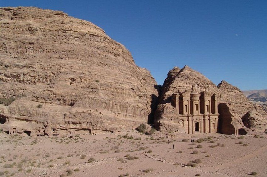 A desert landscape with ancient rock-cut architecture, including a large rock formation and a carved structure. 1