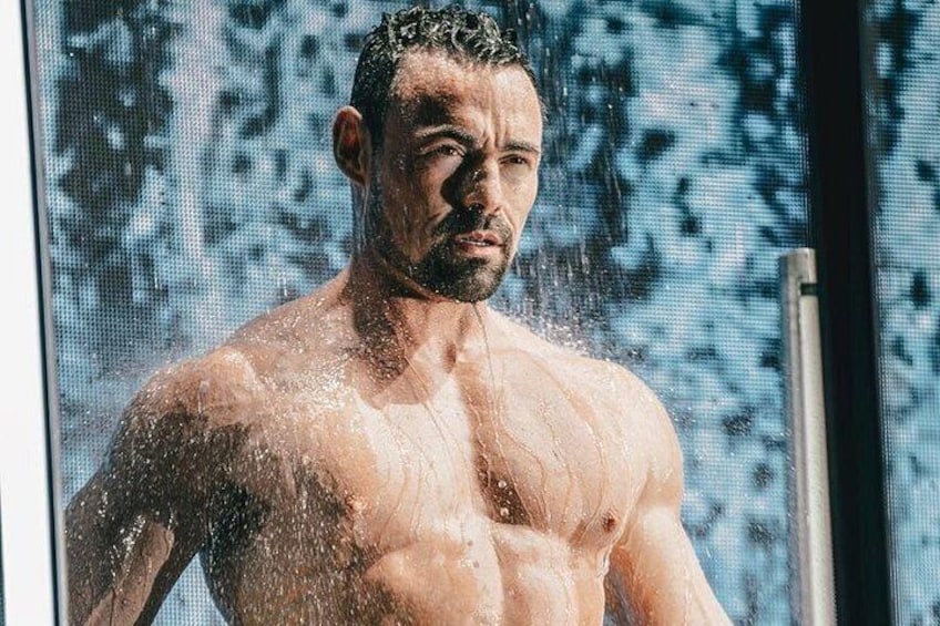 A muscular man in a shower with water droplets visible. 5