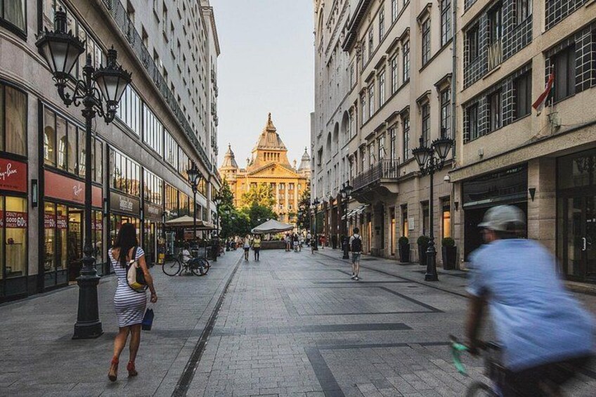 A city street with buildings, a tram, and people walking. 5