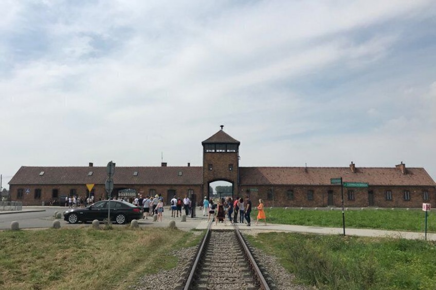 A train station with a brick building, a tower, and a crowd of people. 5