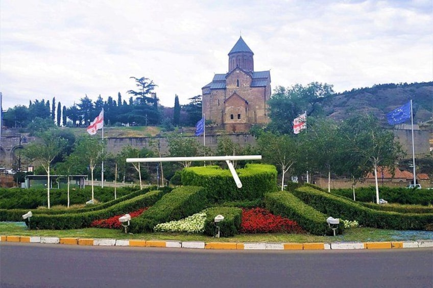 Una chiesa con un campanile, circondata da giardini curati e bandiere. 3