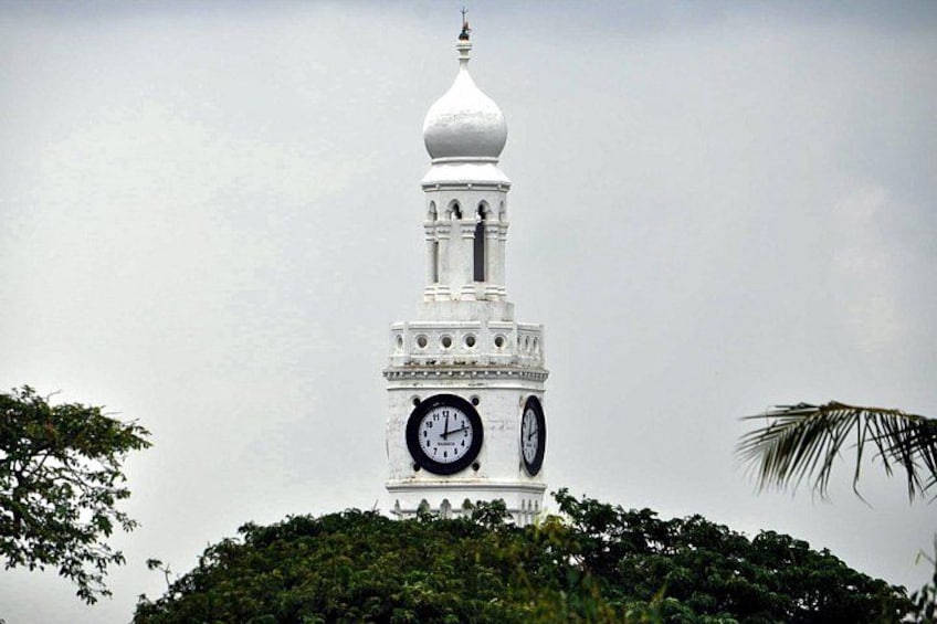 A white clock tower with a dome on top, surrounded by greenery. 2