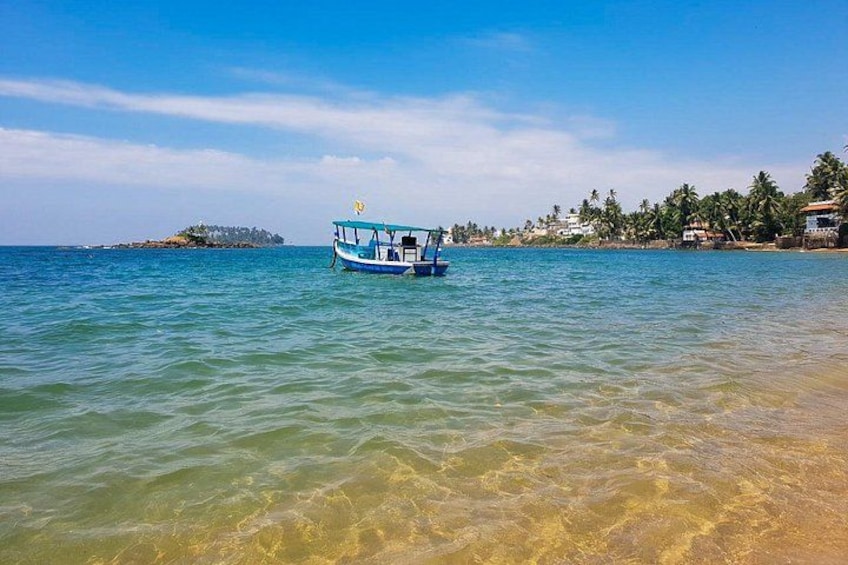 A clear blue sea with a boat in the foreground and a small island in the distance. 1
