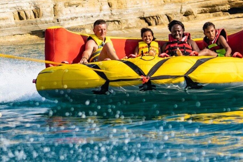 Een groep mensen op een gele luchtbed in het water, met rotsformaties op de achtergrond. 1
