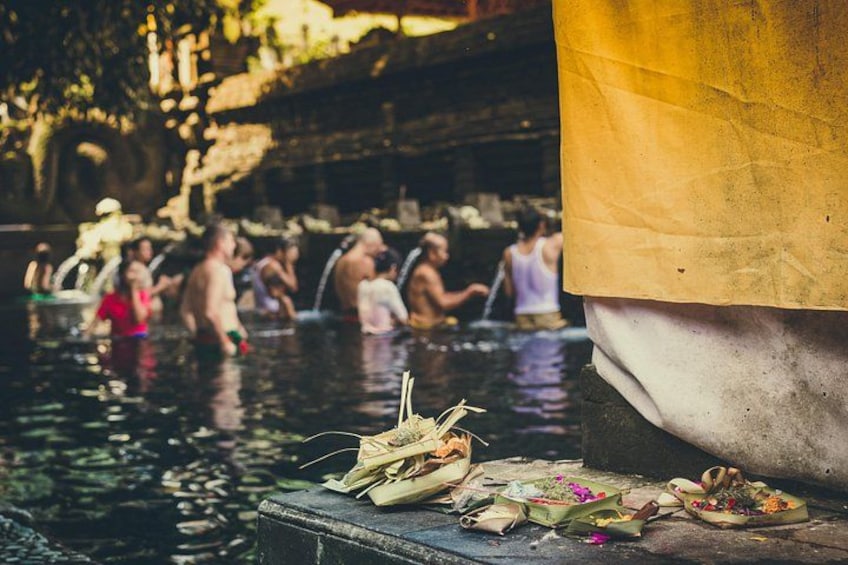 En grupp människor i en naturlig pool, med en stenplattform i förgrunden. 5