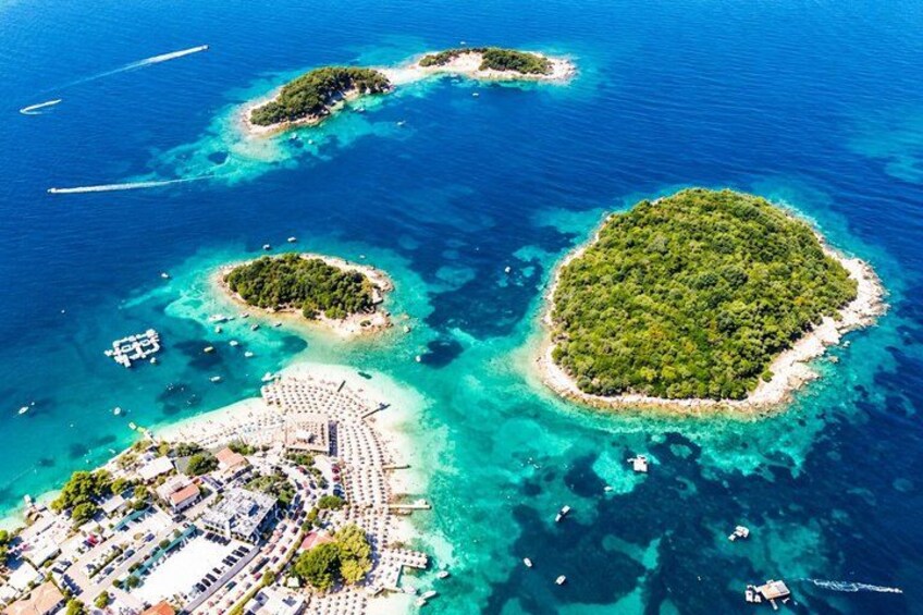 An aerial view of a tropical island with clear turquoise waters, a large central island, and smaller surrounding islands. 1