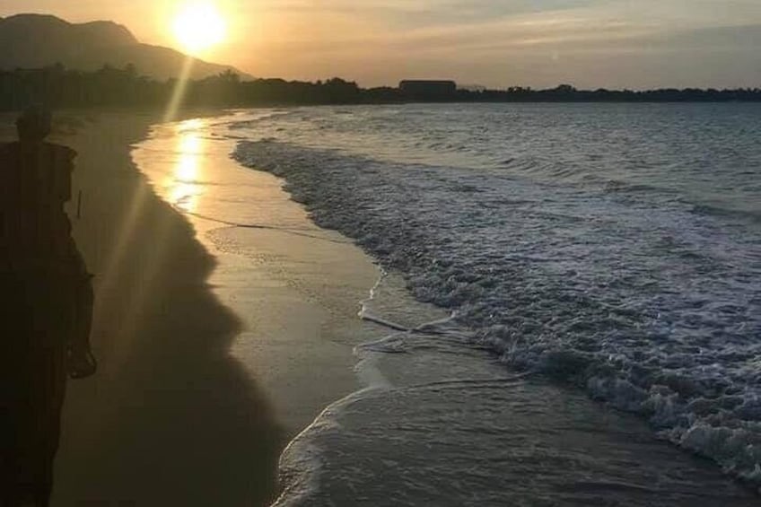 Ein Sonnenuntergang über einem Strand mit Wellen, einer fernen Küste und einem Berg im Hintergrund. 4