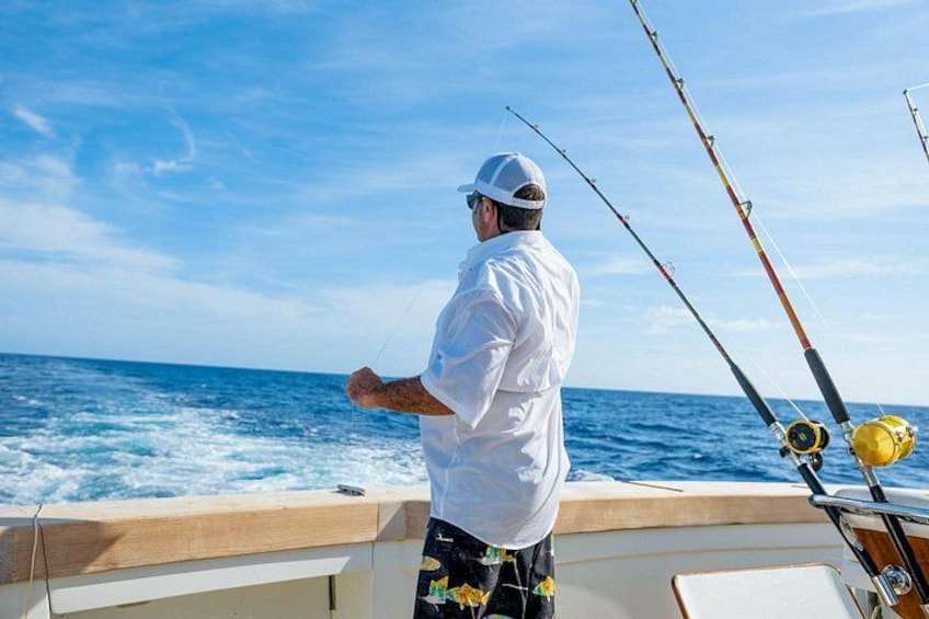 Un hombre pescando en un bote, con el océano al fondo. 5