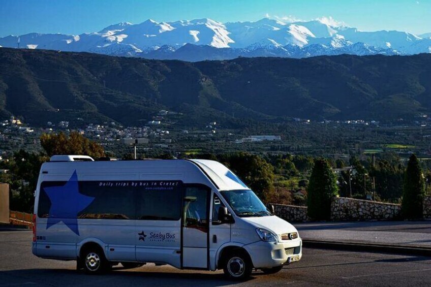 A white van with a blue star and text on the side parked on a road with a mountainous landscape in the background. 2