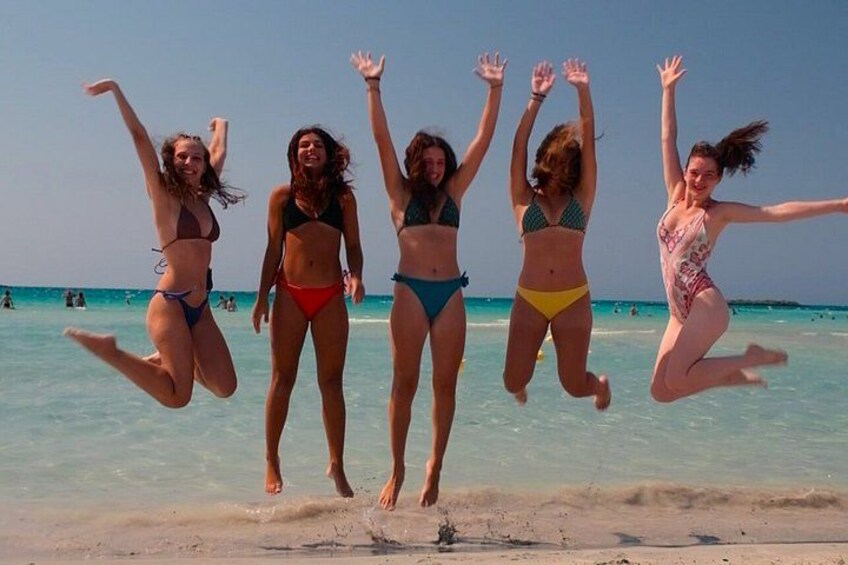 Cinco personas saltando en el aire sobre una playa. 5