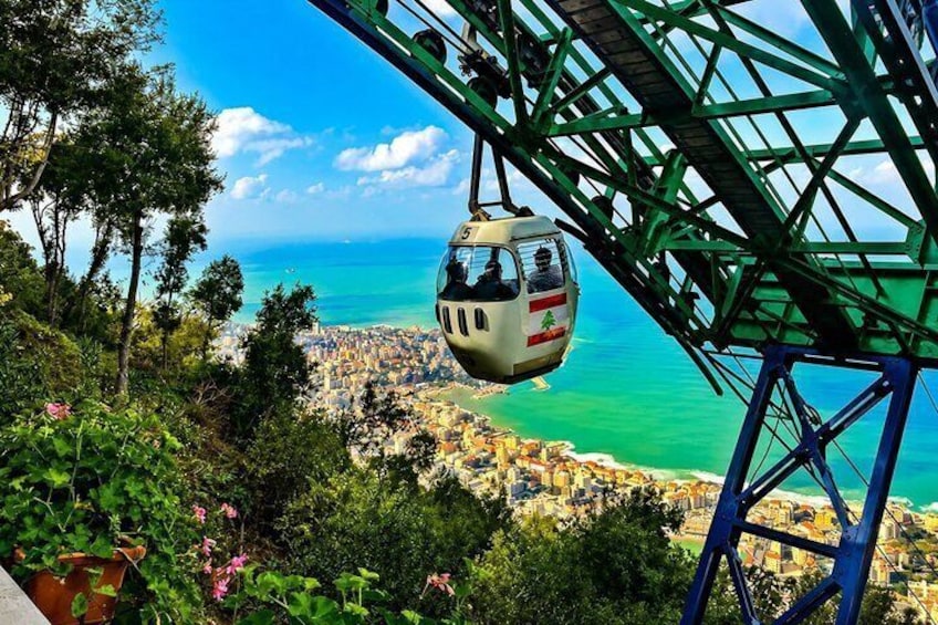 Una funivia sopra una città costiera, con vista chiara sull'oceano e un paesaggio montuoso. 1