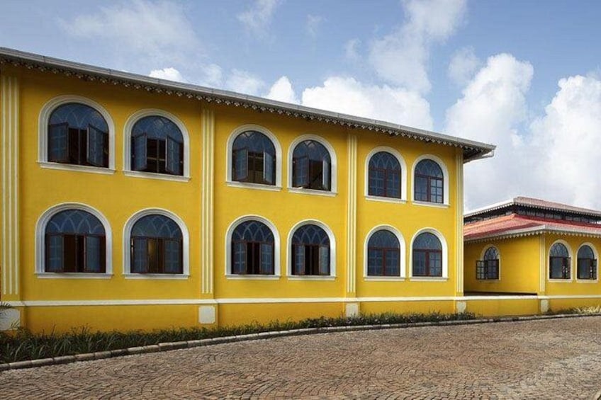 A yellow building with arched windows and a cobblestone path. 3