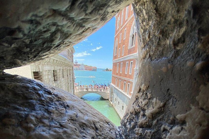 A stone archway, a bridge, and buildings by the water. 1