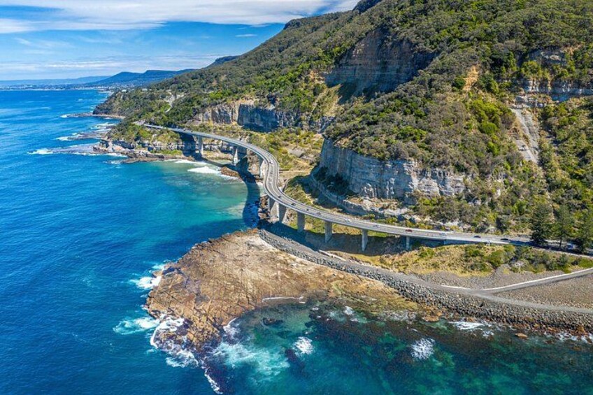 Una autopista costera con un puente sobre el océano, rodeada de acantilados y vegetación. 3