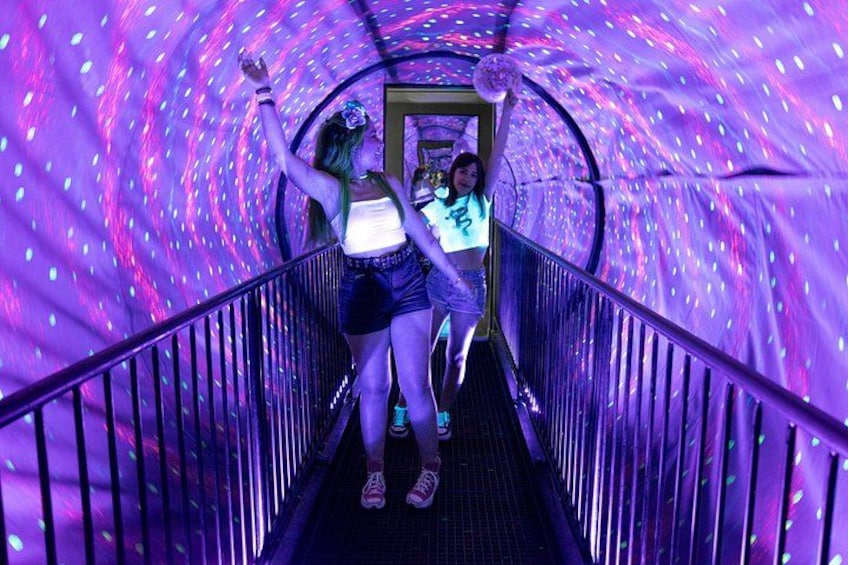 En tunnel med lilla belysning og gelænder. 1