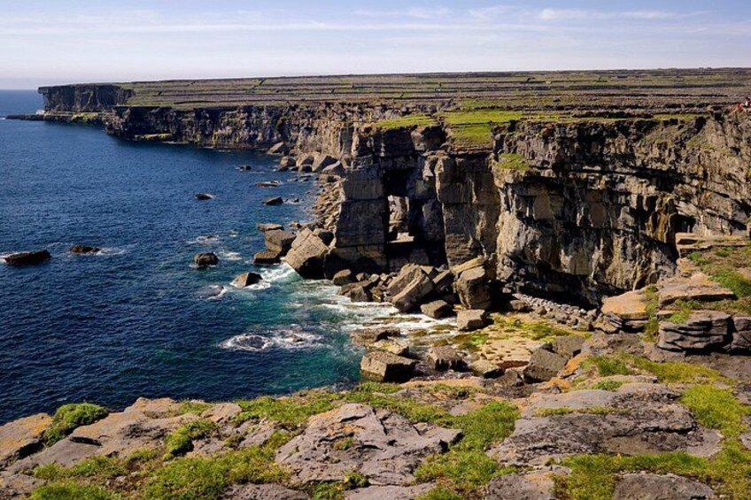 A coastal cliff with rocky formations and waves crashing against the base. 2