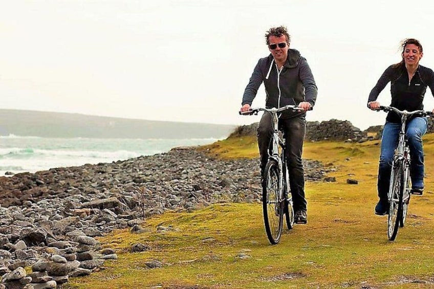 Two people riding bicycles on a rocky coastal path with the ocean in the background. 5
