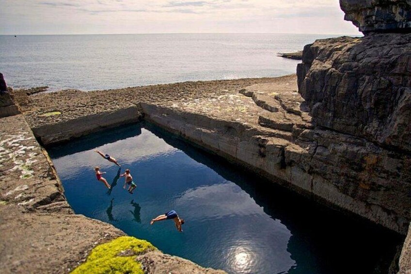 A natural pool surrounded by rocky cliffs with people swimming. 3