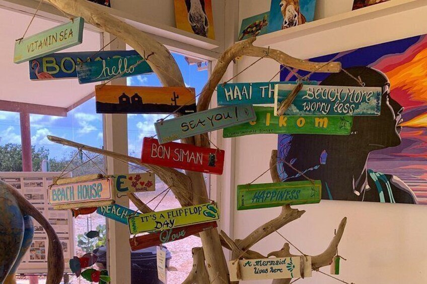 A tree with colorful signs attached to it, including phrases like 'Vitamin Sea' and 'Beach House.' 1
