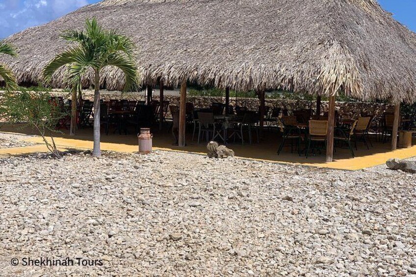 Un restaurant situé en bord de mer, doté d’un toit de chaume et de tables en plein air. 5