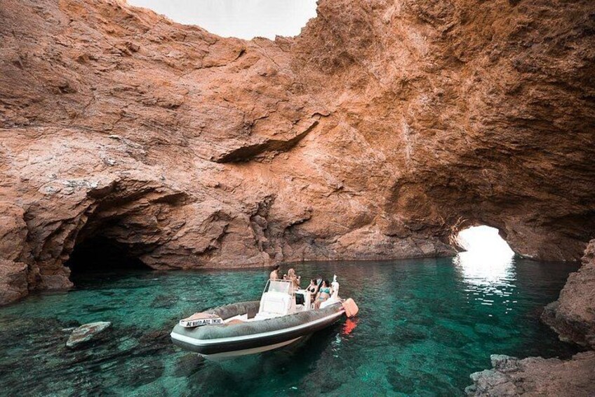 A boat with people on a rocky coastline with clear water. 3