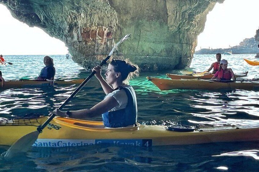 People kayaking in a cove with a large rock formation in the background. 5
