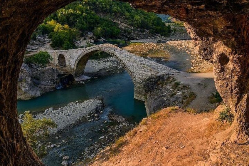 A stone bridge over a river, surrounded by rocky terrain and greenery. 5