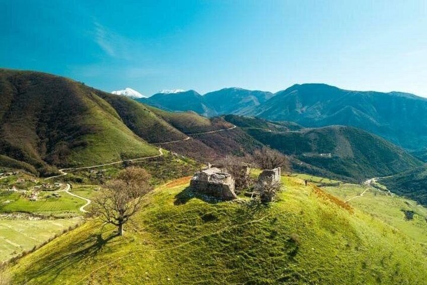Een bergachtig landschap met een stenen gebouw op een heuvel. 4