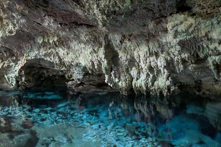 A cave with stalactites and a clear pool of water. 4