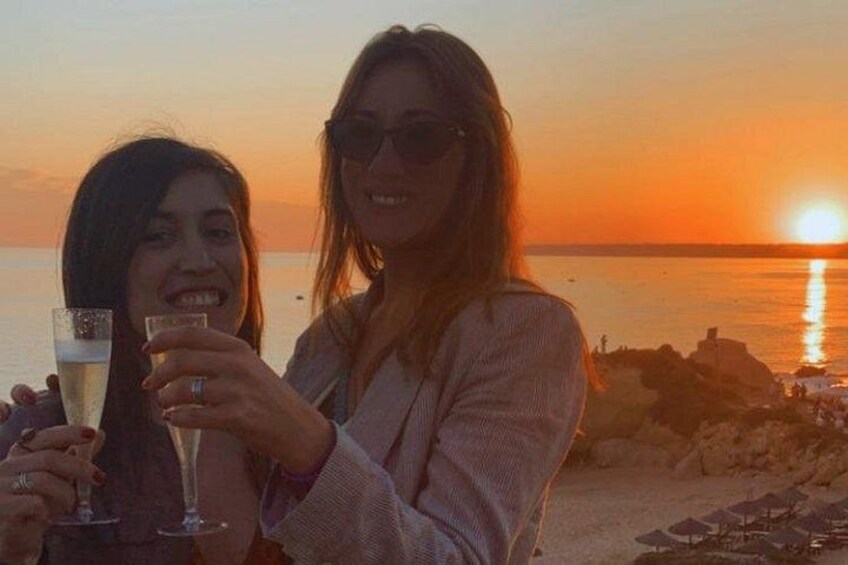 Due persone brindano con calici di champagne sulla spiaggia al tramonto. 3