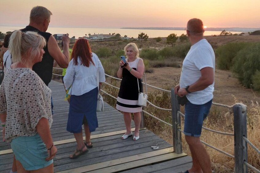 Un gruppo di persone su una passerella di legno in riva all'acqua al tramonto. 5