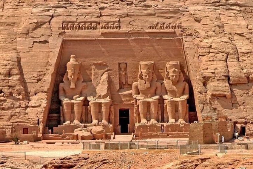 Een groot, in de rots uitgehouwen tempel met beelden van farao's en een brede deuropening. 2