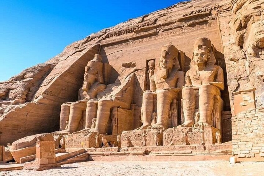 A large rock formation with carved statues of seated figures. 3