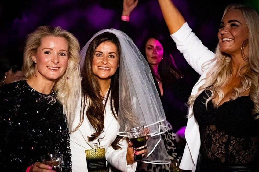 Een persoon met een glas in de hand, een persoon in een witte outfit en een derde persoon in een zwarte jurk. 5