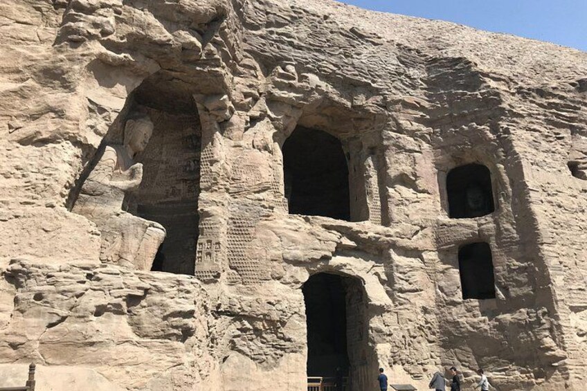 A rock face with carved niches and a statue. 2