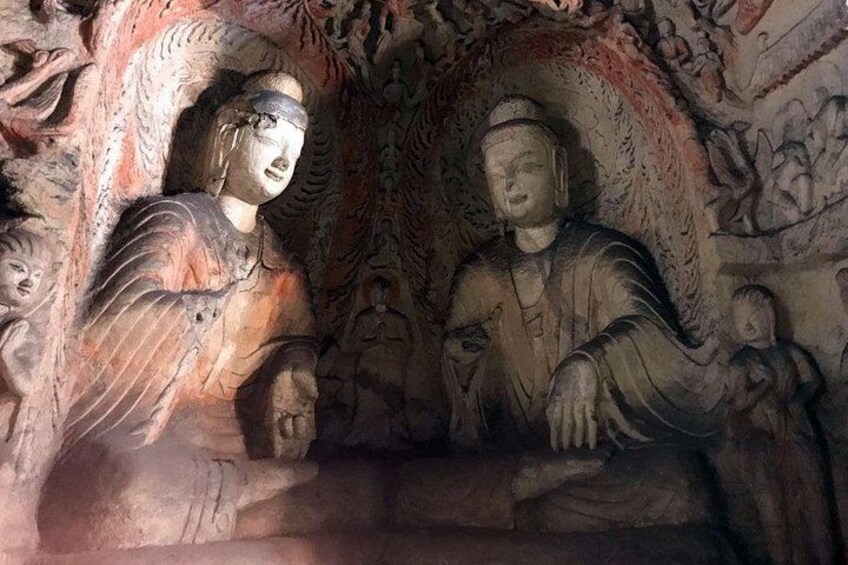 A cave with ancient carvings of Buddha statues and figures. 4