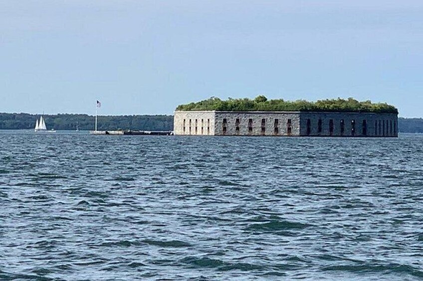 Een groot, rechthoekig gebouw van steen met een vlag erop, omringd door water. 4